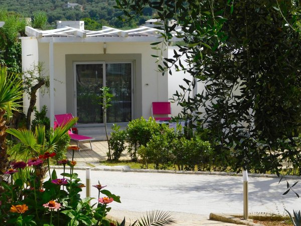 Casa bianca circondata da fiori e alberi.