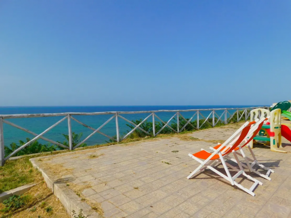 Due sdraio arancioni rivolte verso il mare.