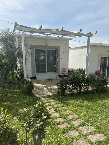 Casa bianca con pergolato e giardino.