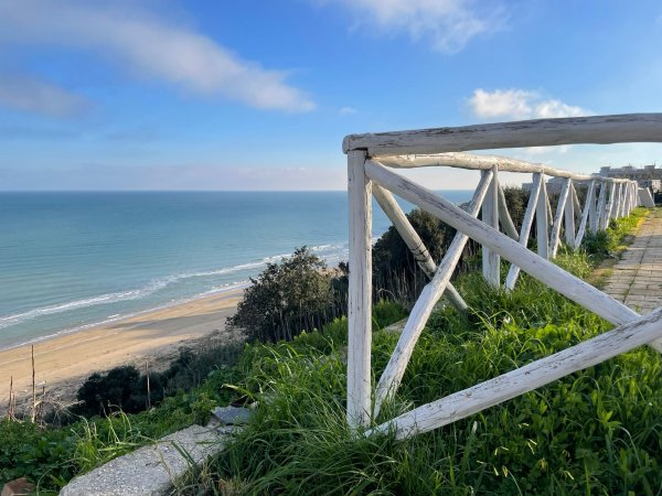 Vista mare da una staccionata in legno bianca.
