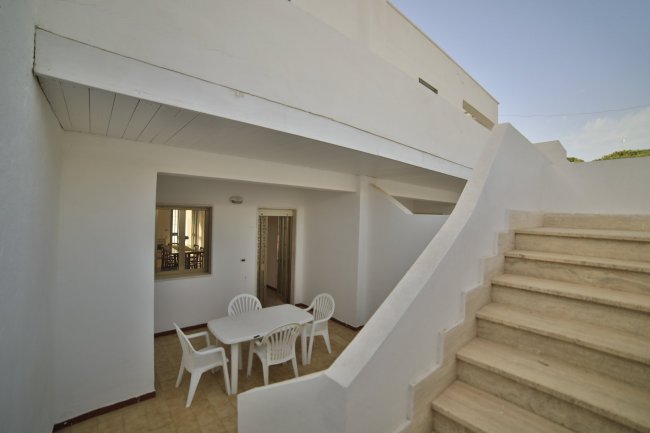 Patio esterno con scala e tavolo bianco.