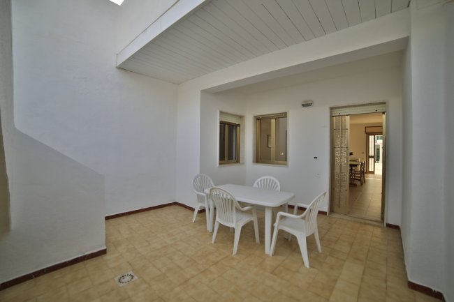 Cortile con tavolo e sedie bianche in plastica.