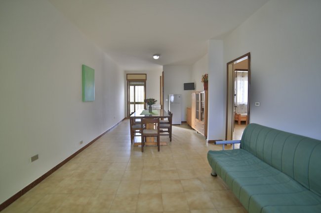 Soggiorno con tavolo, sedie e divano verde.