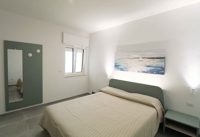 Camera da letto con letto matrimoniale e quadro.