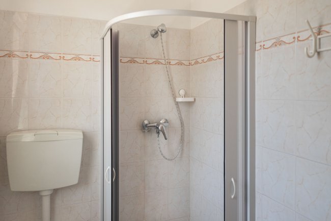 Bagno con doccia e piastrelle chiare.