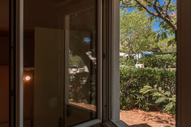 Vista di un giardino verde attraverso una finestra aperta.