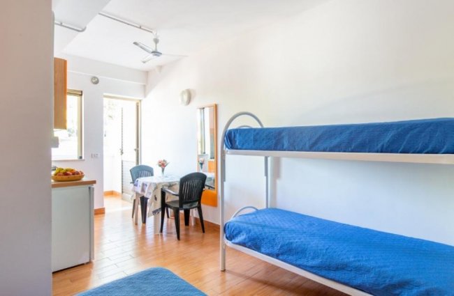 Zona letto con letti a castello blu e tavolo.