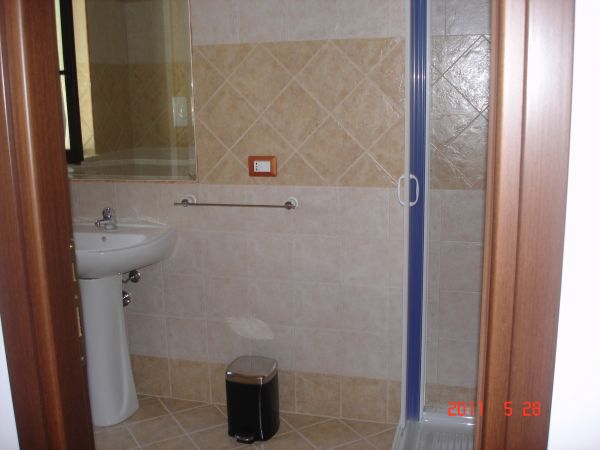 Bagno con lavabo, doccia e cestino.