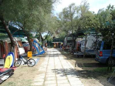 Sentiero in un campeggio con camper e tende tra gli alberi.