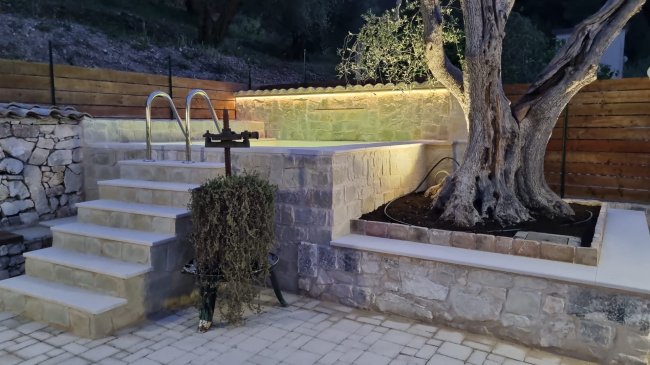 Area piscina con albero e muretto.