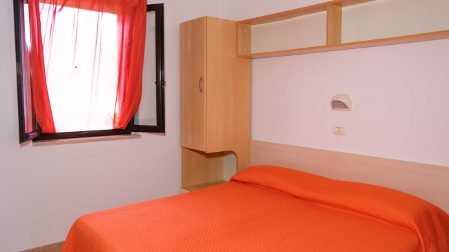 Camera da letto con letto matrimoniale e tenda arancione.