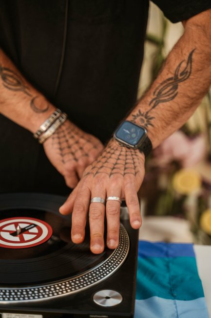 Mani tatuate su un giradischi.