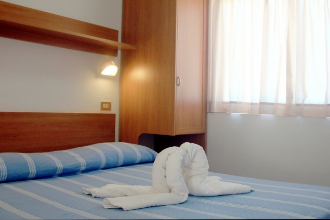 Letto con lenzuola a righe blu e asciugamani a forma di cigno.