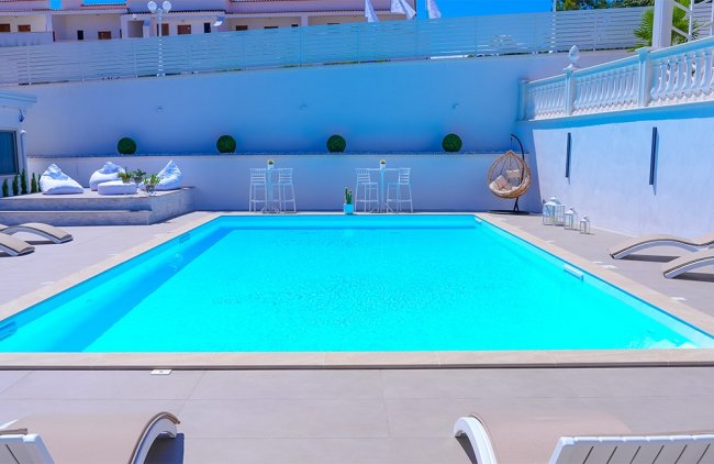 Piscina azzurra con area relax e sedie a sdraio.