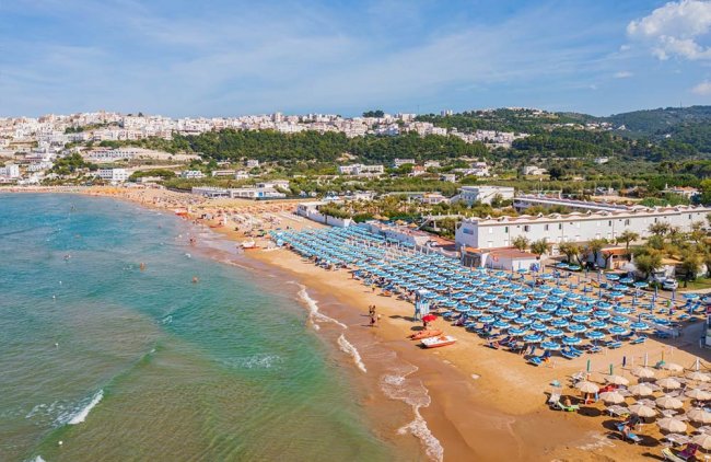 Spiaggia con ombrelloni blu e mare.