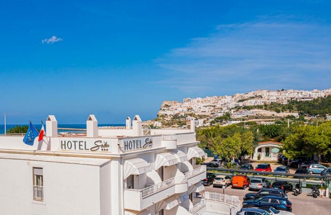 Insegna di un hotel bianco con vista su un paese collinare.