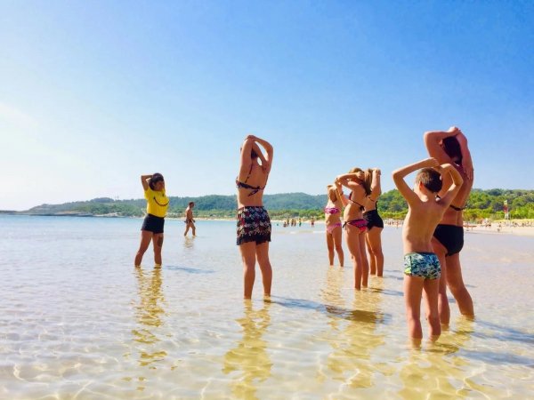 Persone in acqua al mare, con braccia sollevate.