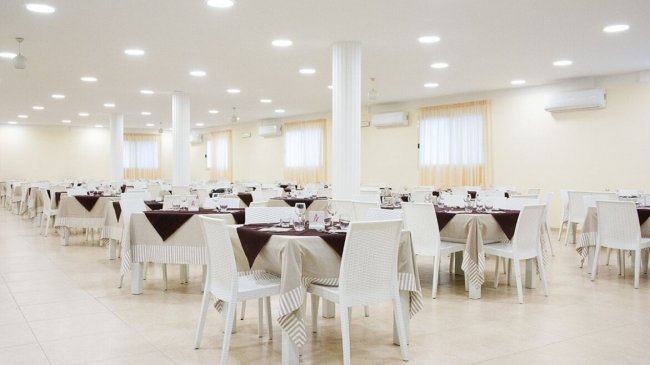 Sala da pranzo con tavoli apparecchiati.