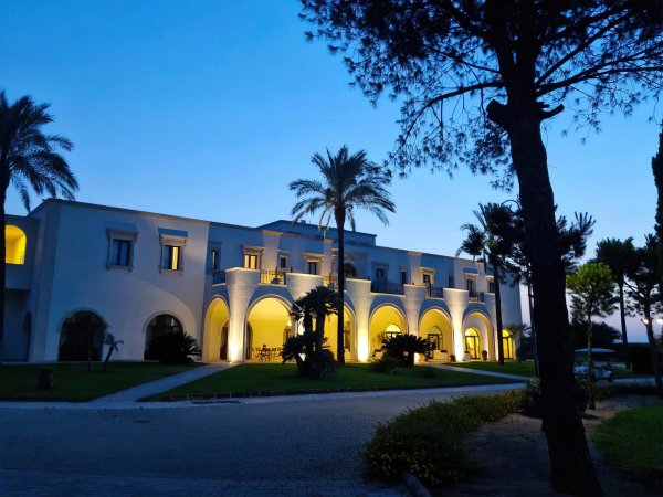 Edificio illuminato di sera con archi e palme.